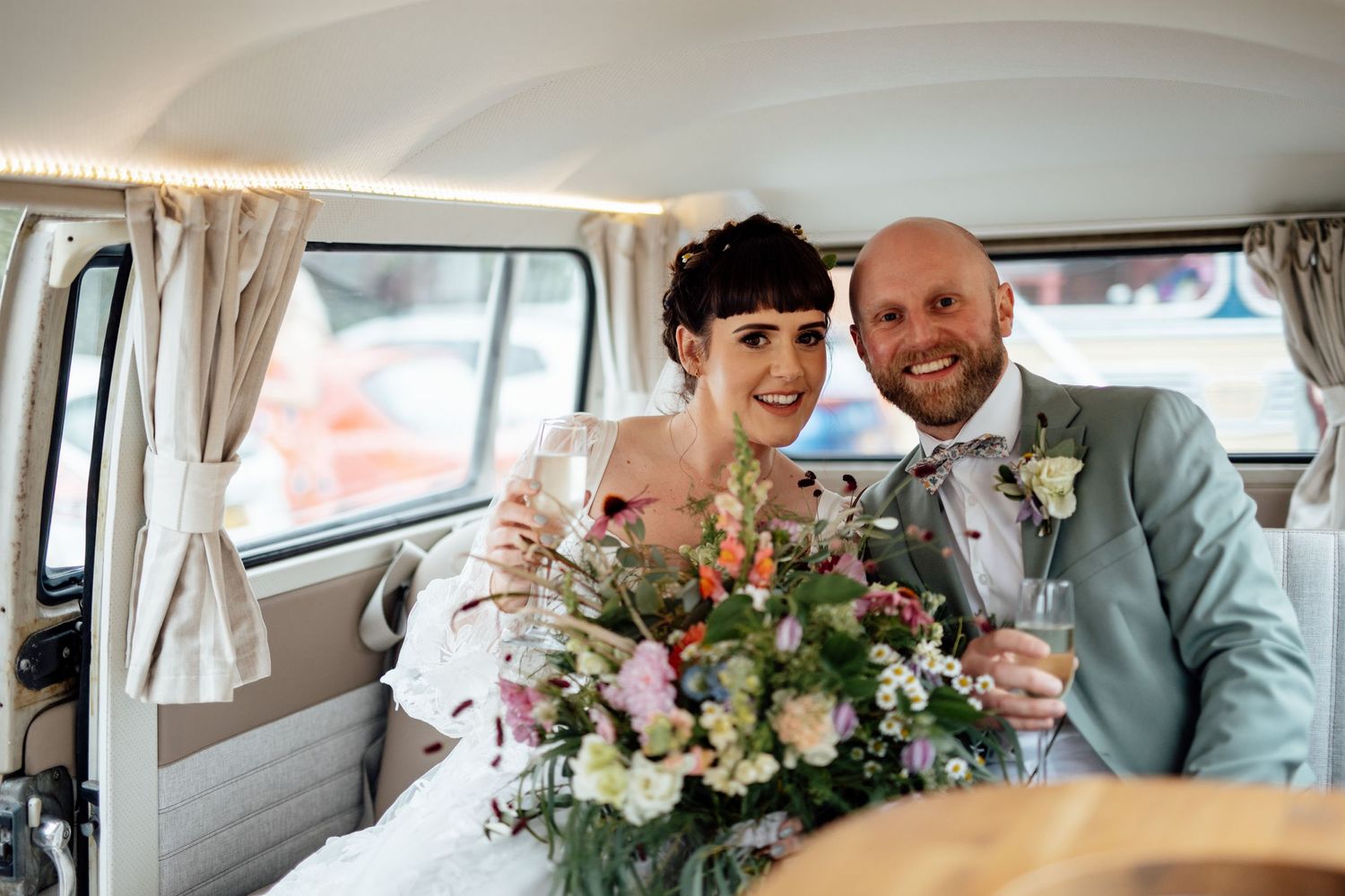 Couple celebrating in a vintage wedding vehicle with floral decorations.