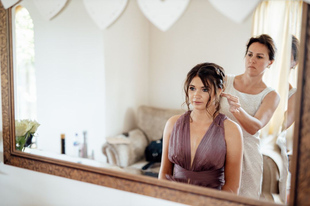 Wedding preparation scene reflected in mirror showing final styling touches.