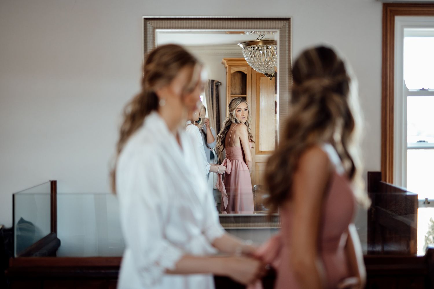 A group of people gather in a bright room during wedding preparations.