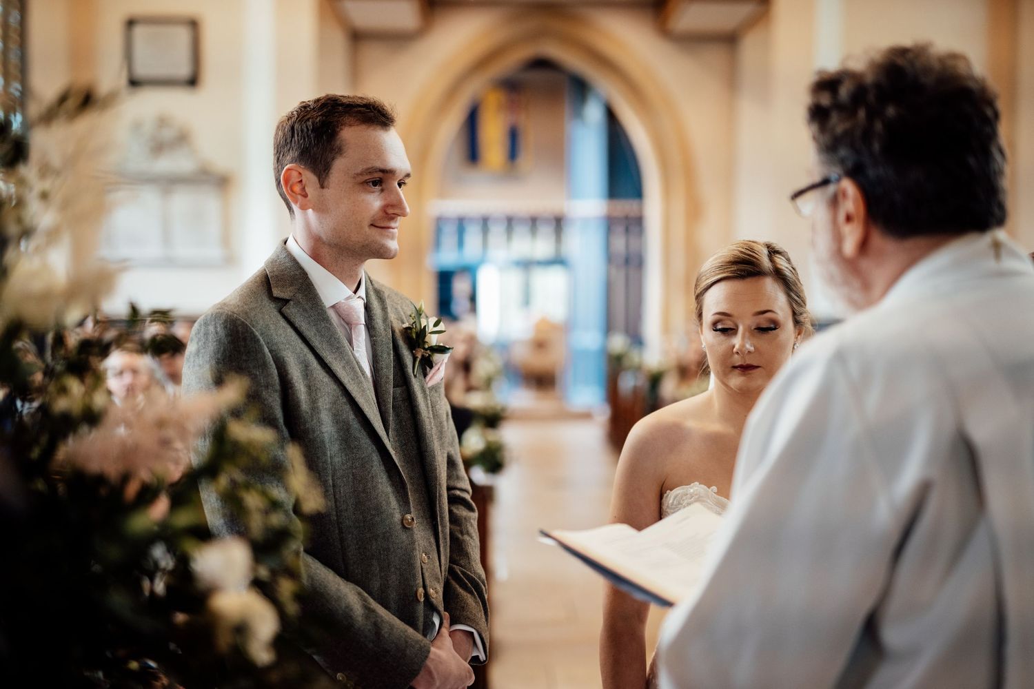 Couple exchanges vows during an intimate indoor wedding ceremony with arched architectural details.