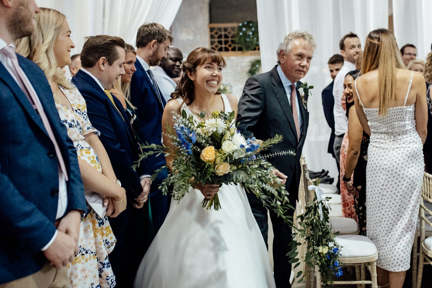 Wedding celebration with guests mingling and dancing in an elegant indoor venue.