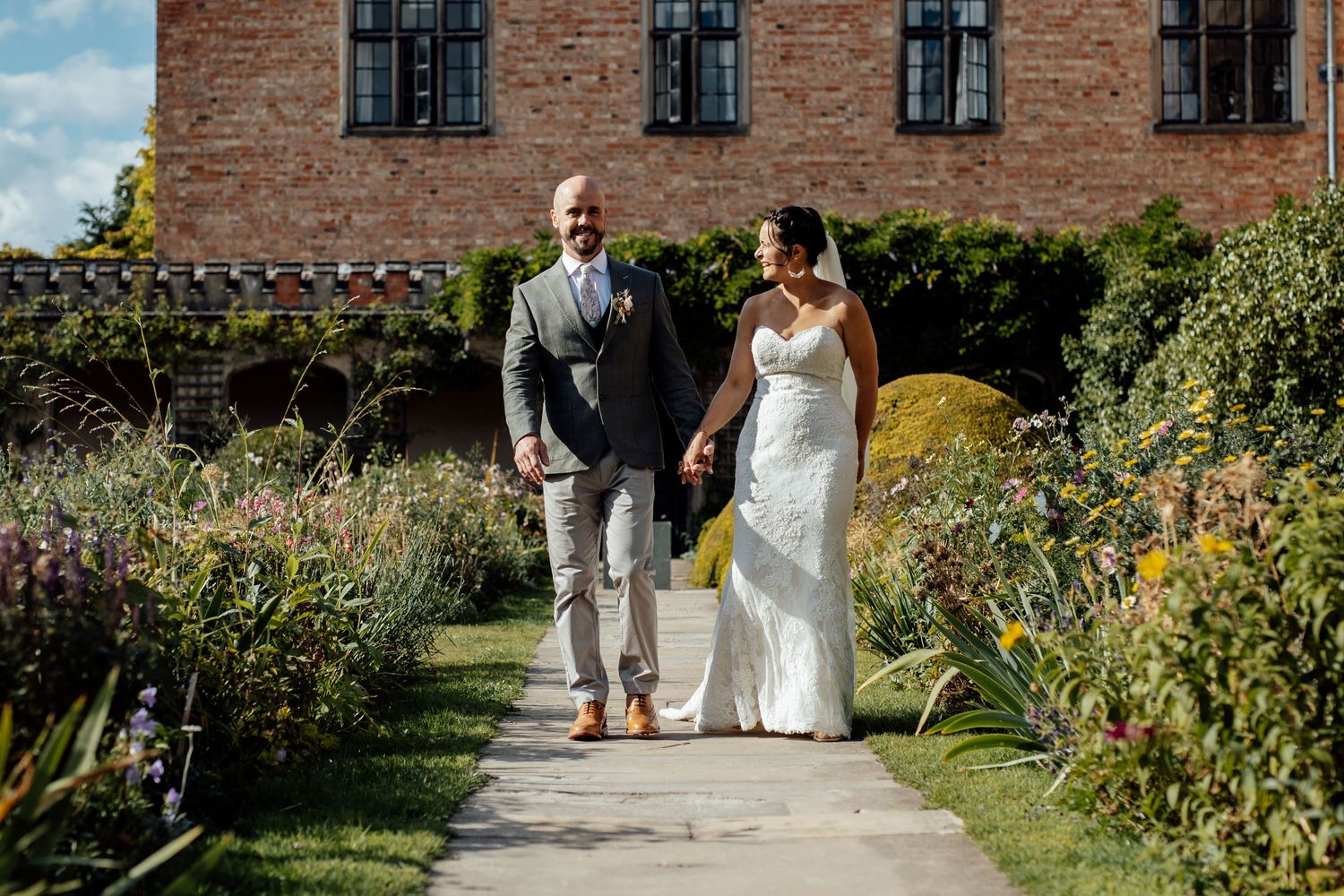 Garden pathway along historic brick building with wedding party.