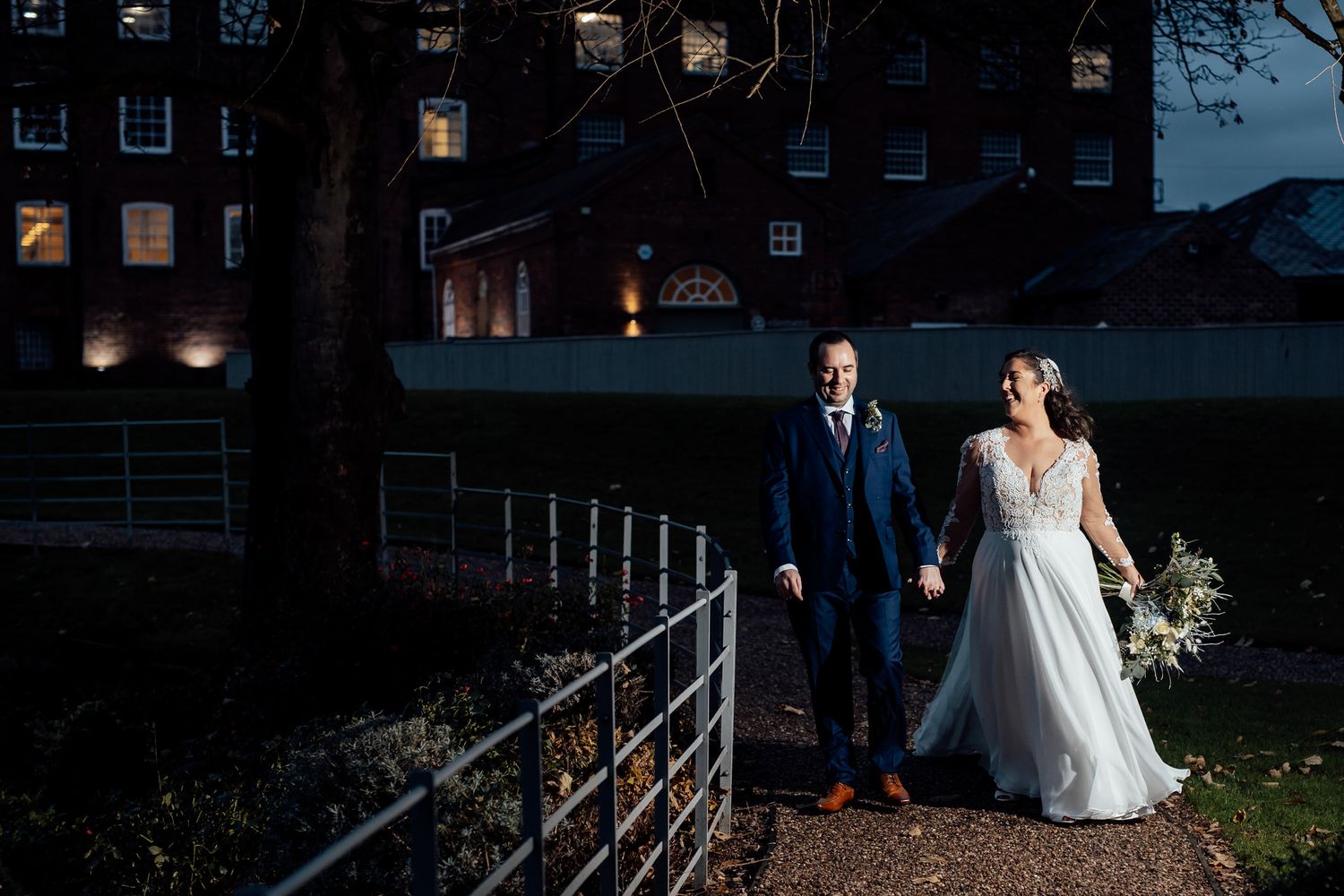 Twilight wedding portraits against dark architectural backdrop with dramatic lighting.