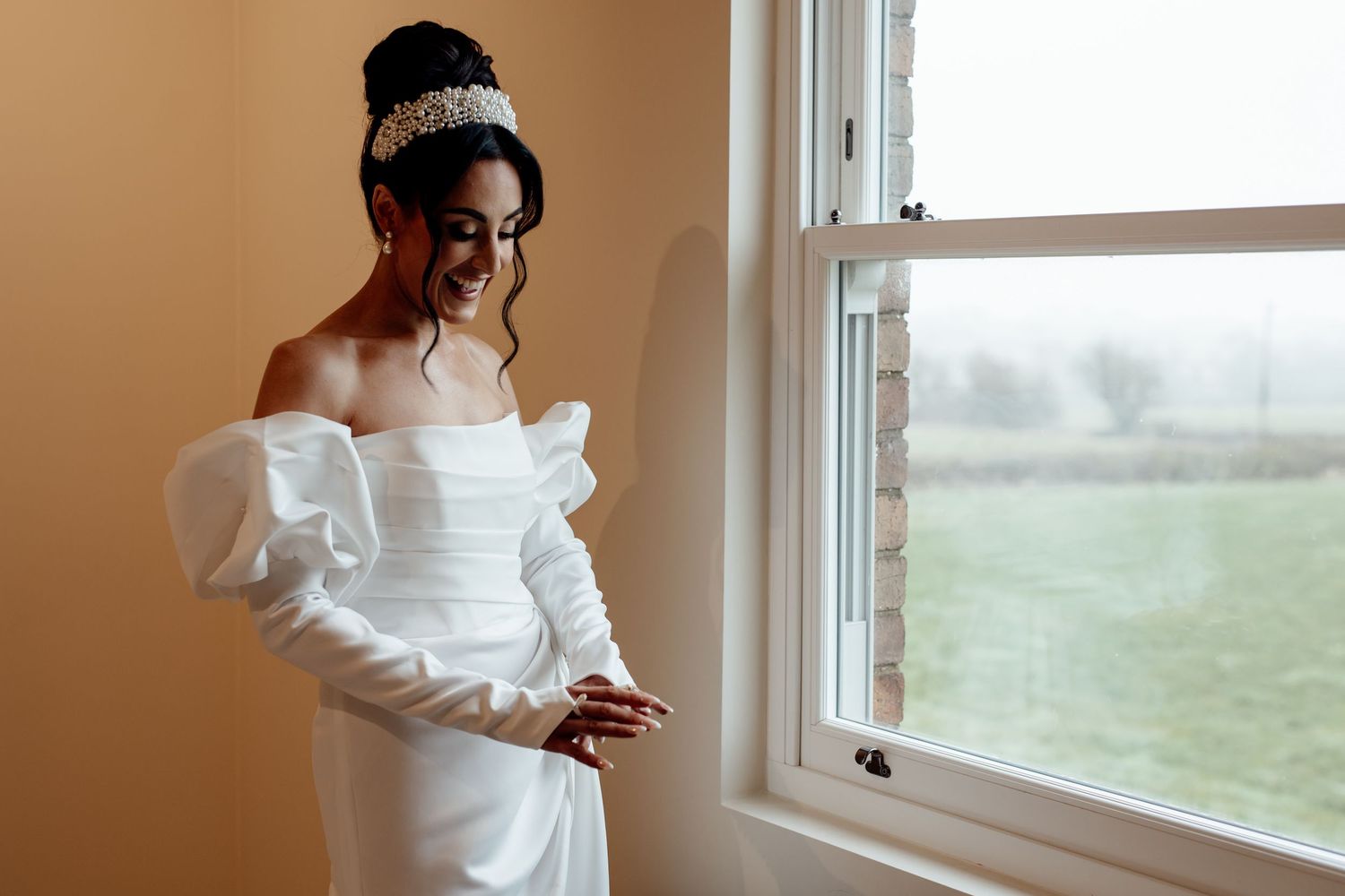 Elegant white wedding dress details against a window with natural light.