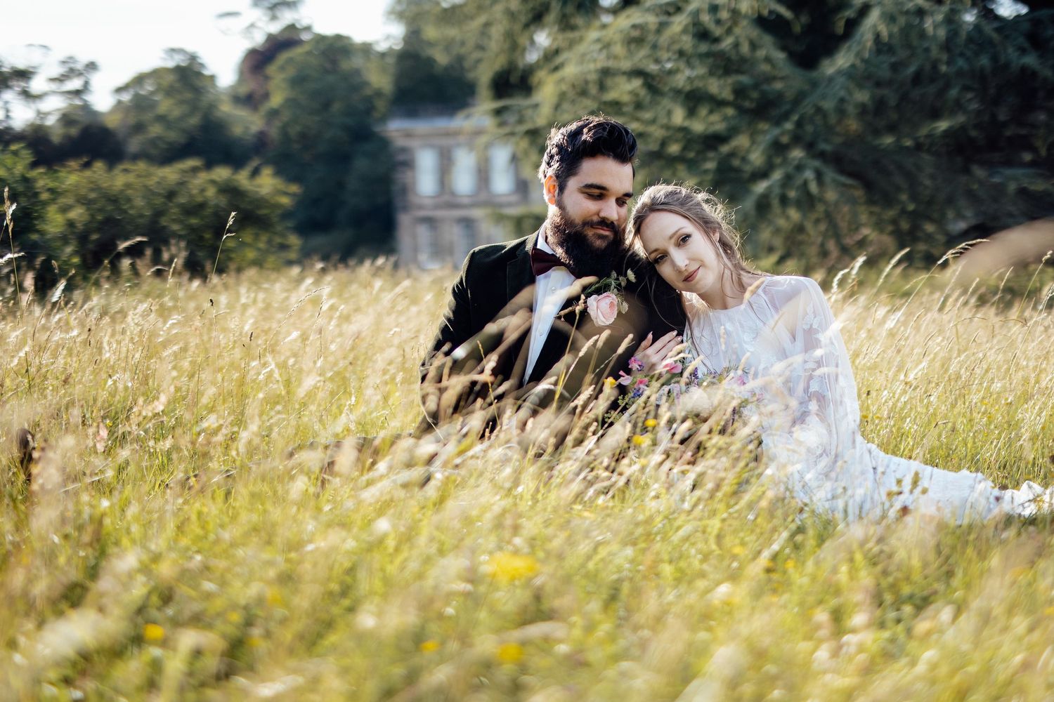 Wedding couple poses in tall golden grass during a romantic outdoor photo session.