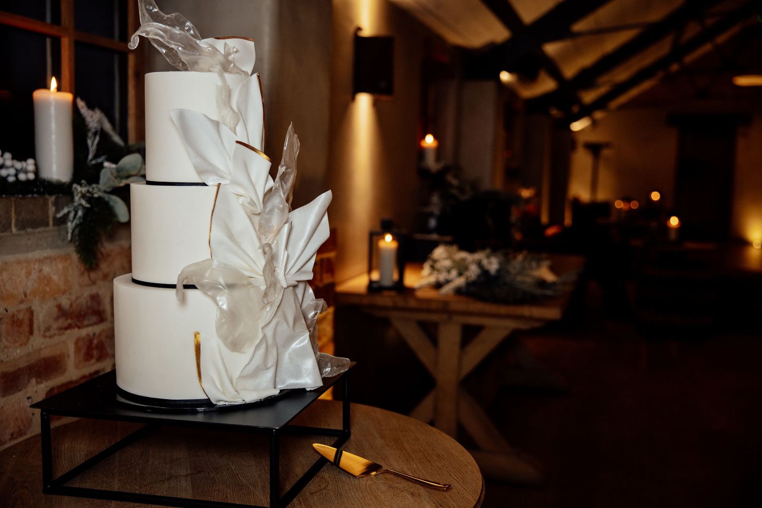 Elegant white wedding cake with delicate floral decorations displayed at an intimate reception venue.