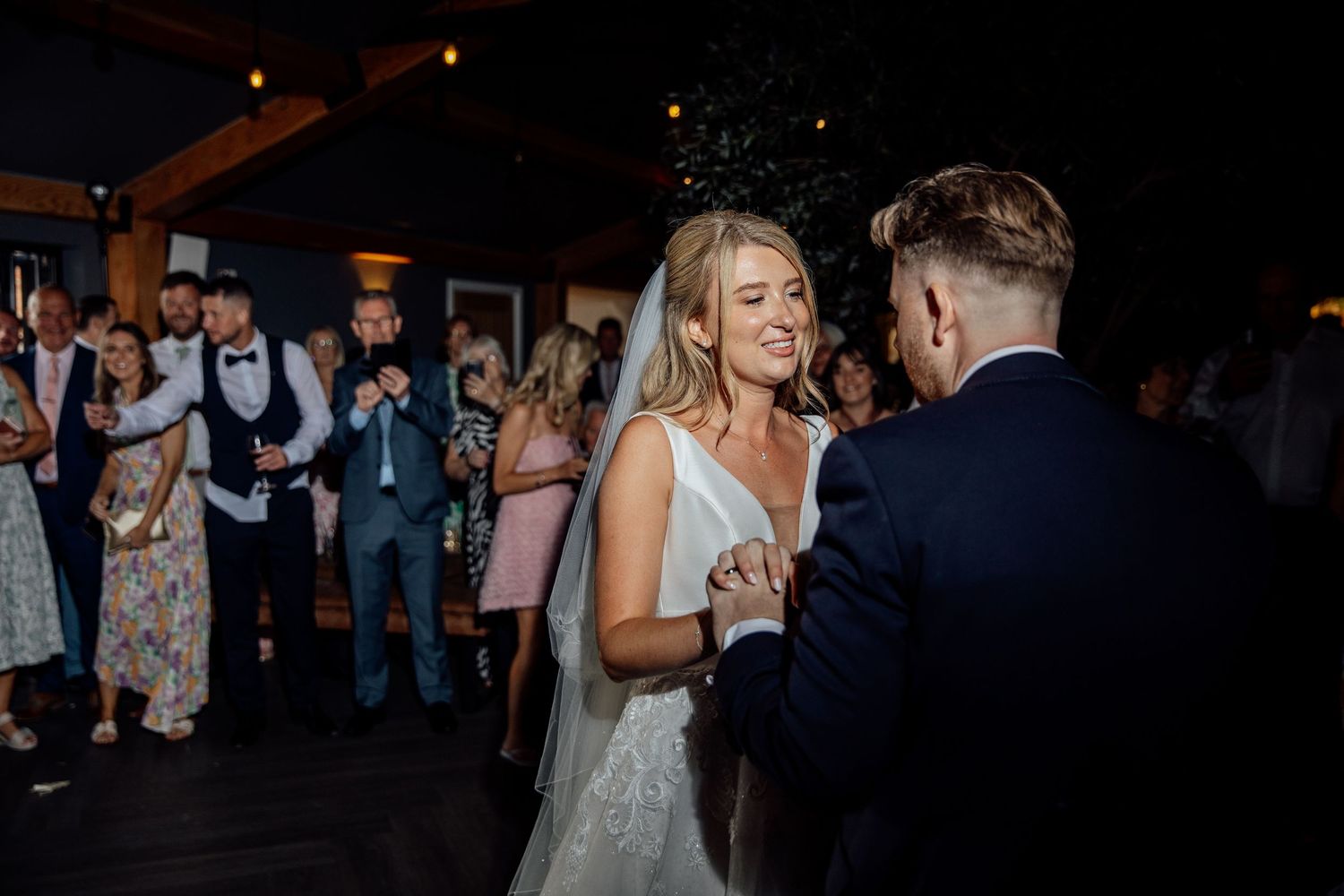 Couples dance together during a dimly lit wedding reception.