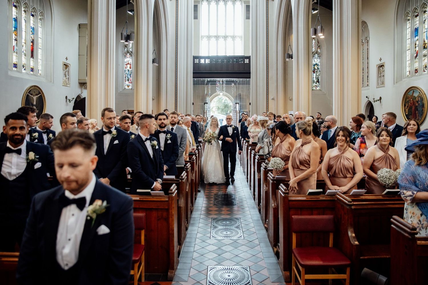 Wedding ceremony in a grand cathedral with guests seated in wooden pews.