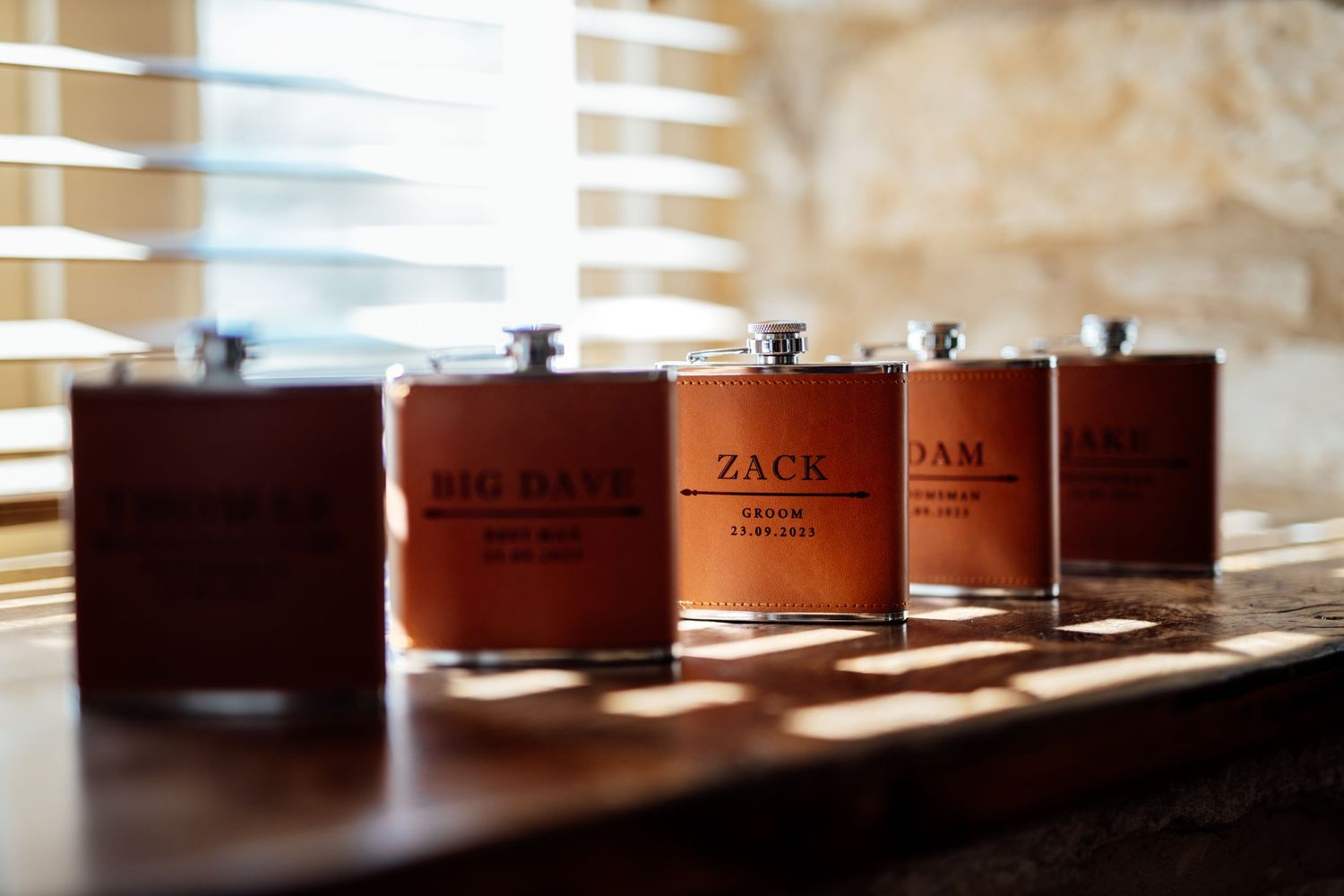 Row of brown leather wedding ring boxes lined up on a wooden surface in natural light.