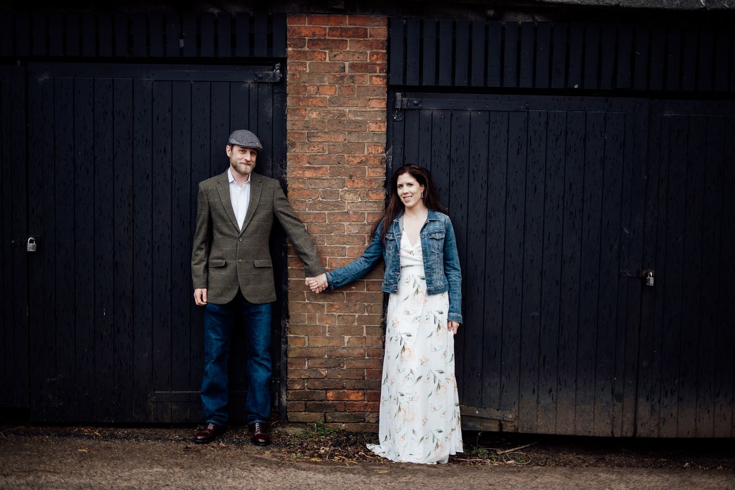 Two people share an intimate moment against a dark wooden wall and brick background.