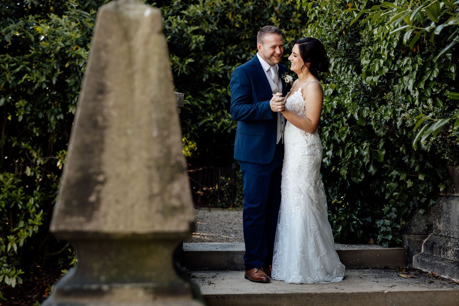 Couple sharing romantic moment in garden setting with lush greenery.