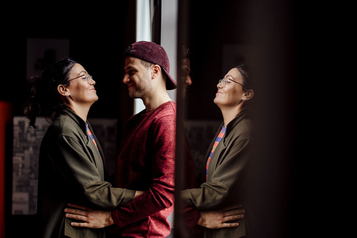 Dramatic low-light portrait session showing intimate couple poses against dark background.