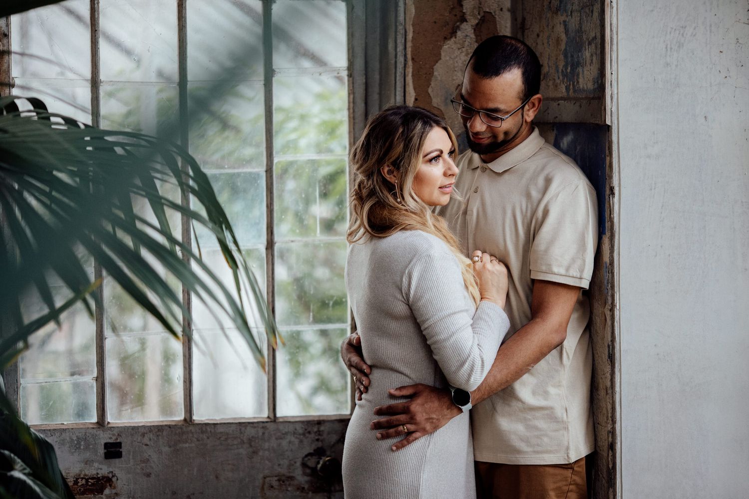 A couple shares intimate moments together in a sunlit indoor space with plant shadows.