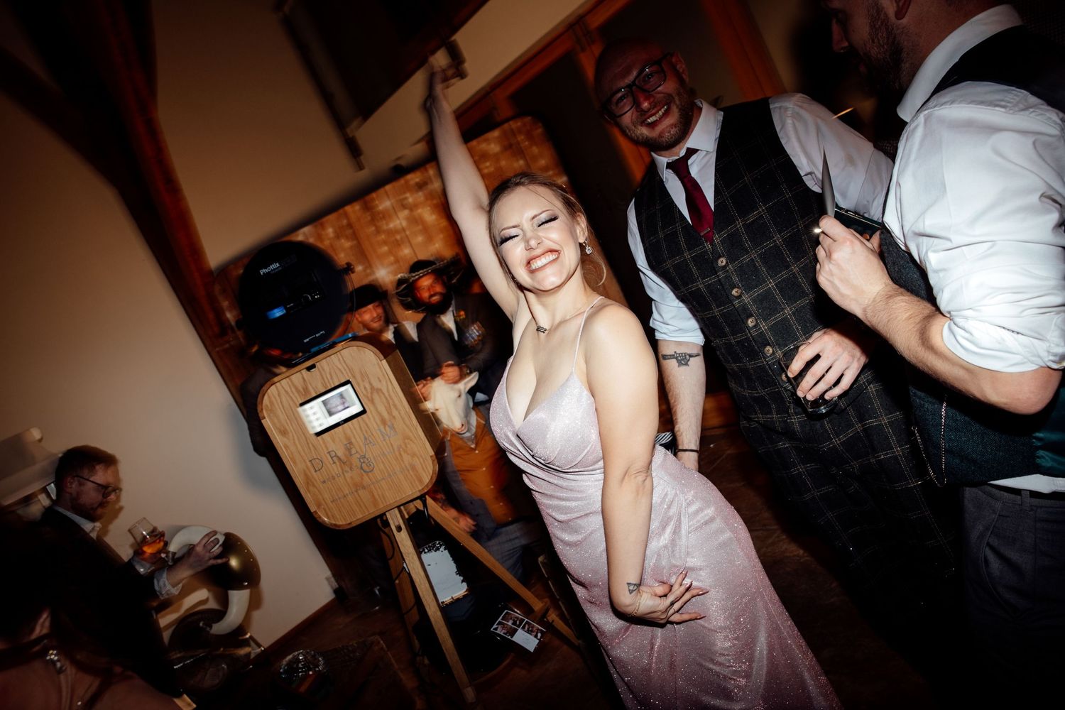 Wedding guests enjoying a lively dance party in a dimly lit reception venue.
