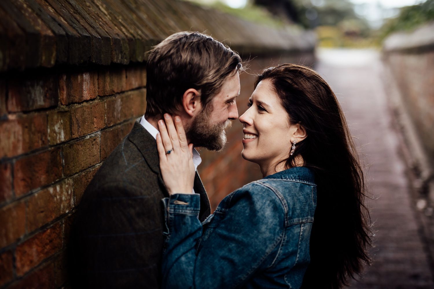 A romantic couple shares close intimate moments along a brick-lined path.
