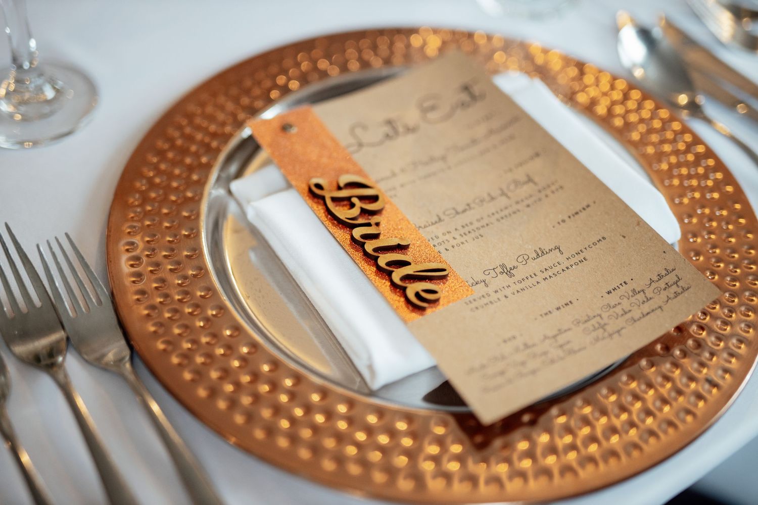 Elegant table setting with copper charger plates and menu cards at formal event.