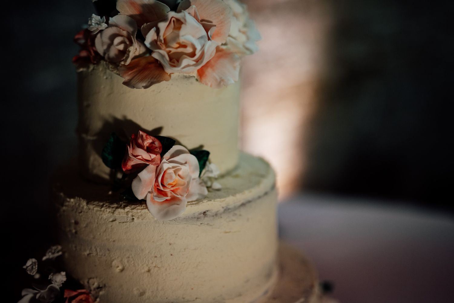 Elegant white wedding cake decorated with delicate pink roses and floral accents.
