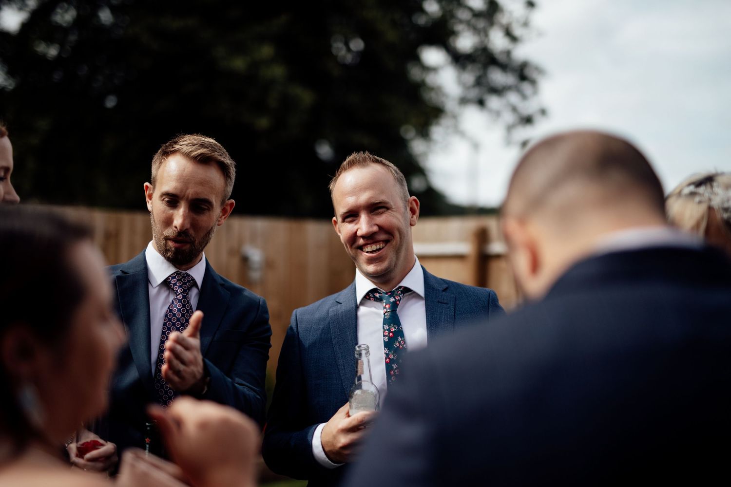 Candid moment of wedding guests laughing and socializing outdoors.