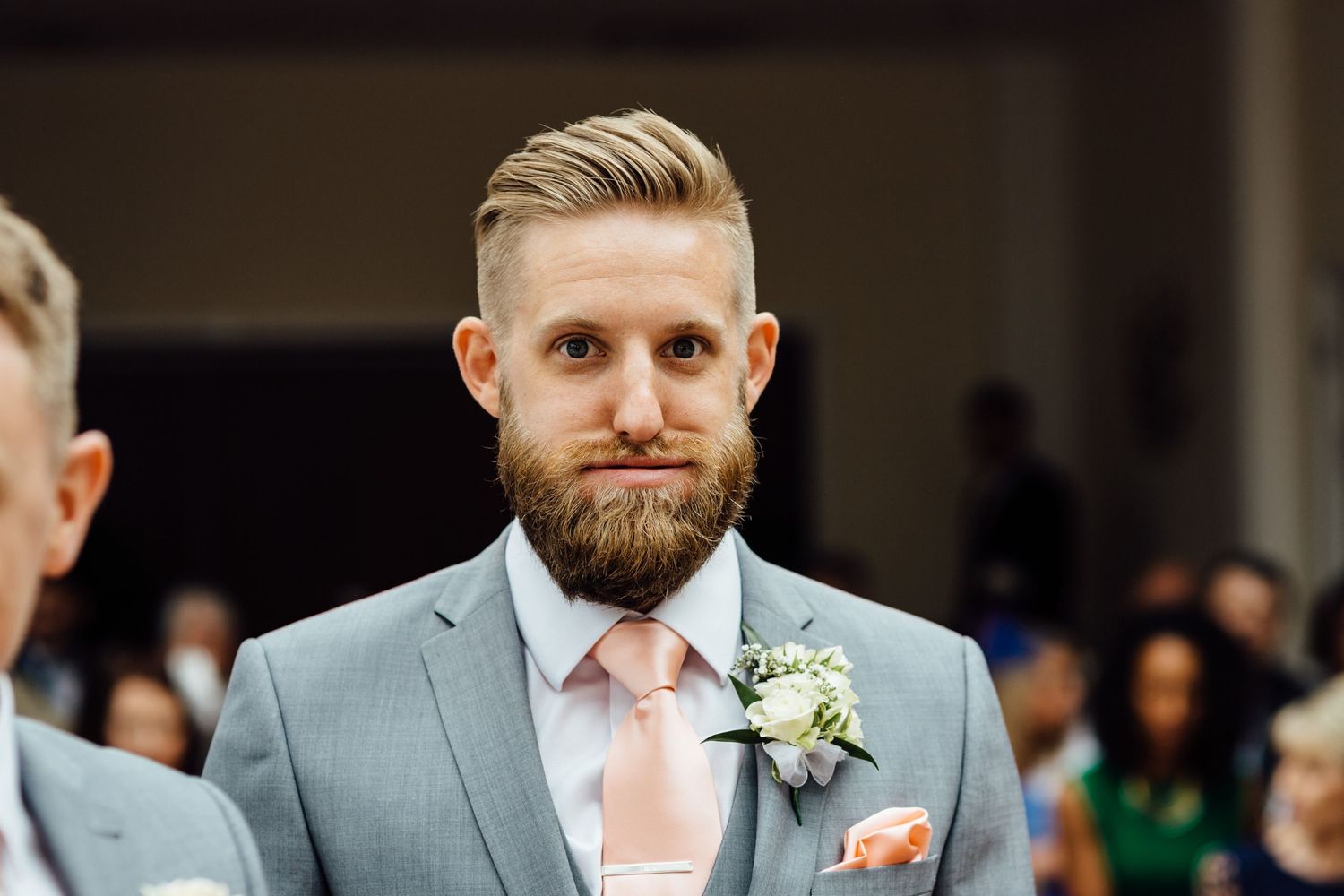 Wedding party members in gray suits and pink ties at formal ceremony.