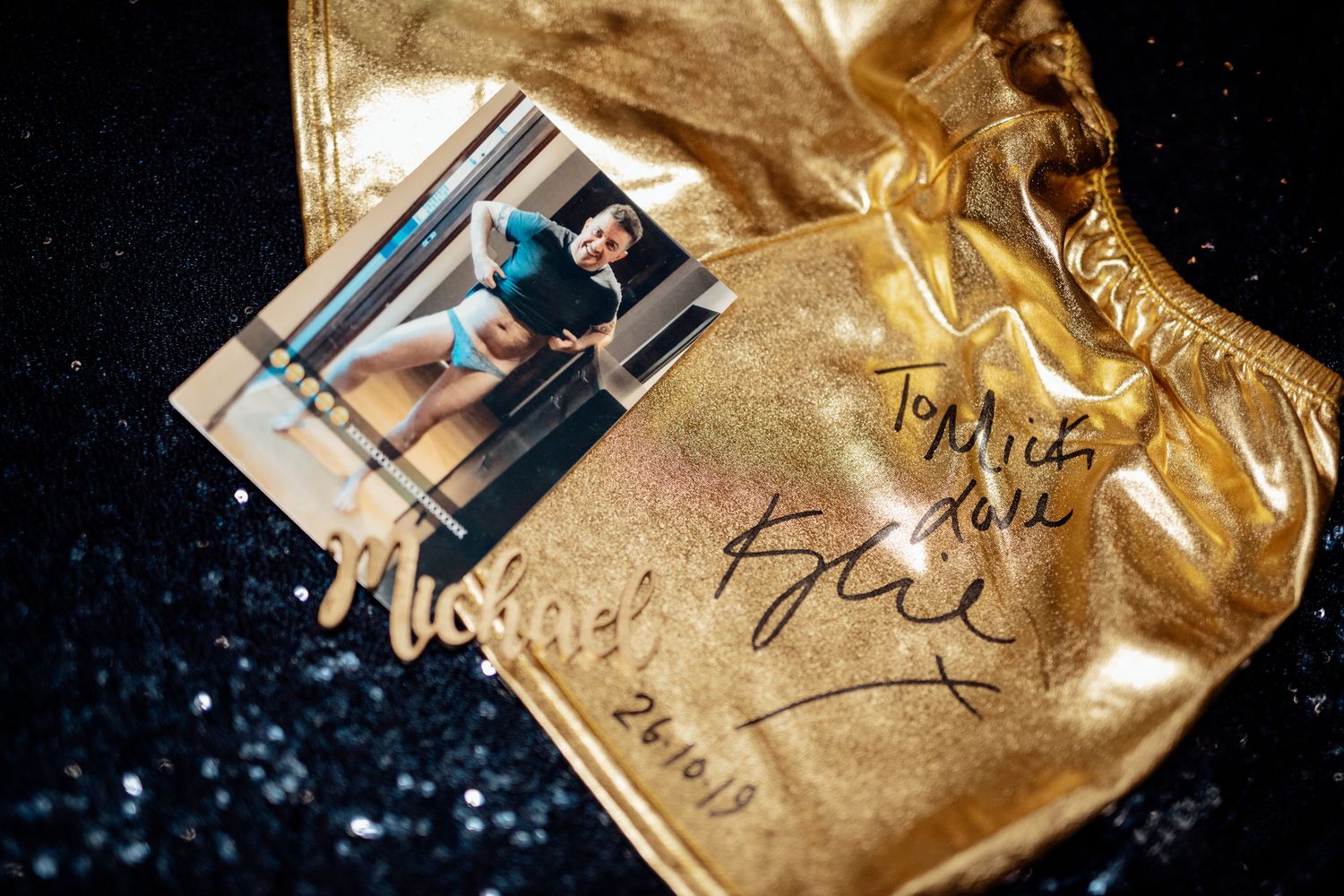 Gold foil wedding favor bags arranged artistically on dark surface.