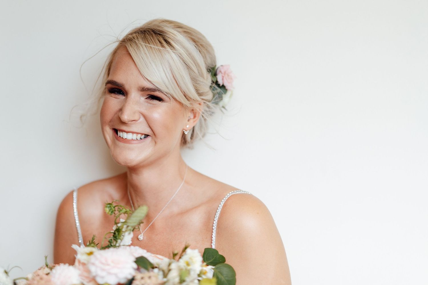 Bridal portrait against white background with floral accents and natural lighting.