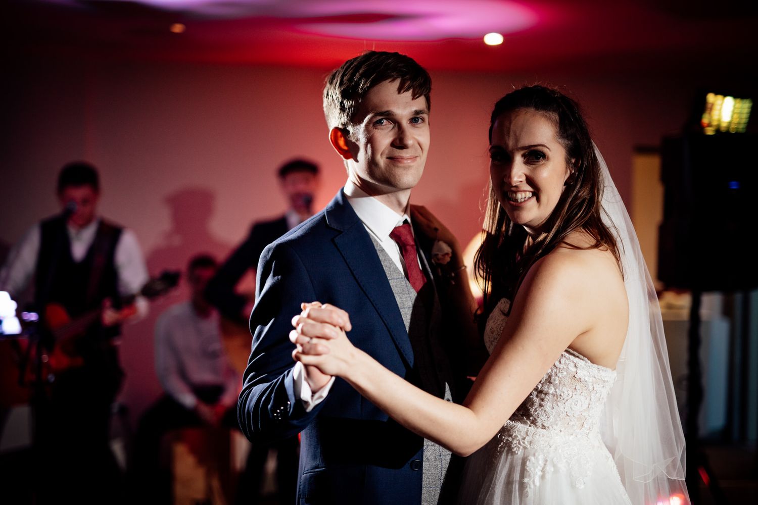 Wedding couples share intimate dances under dramatic red lighting at reception.