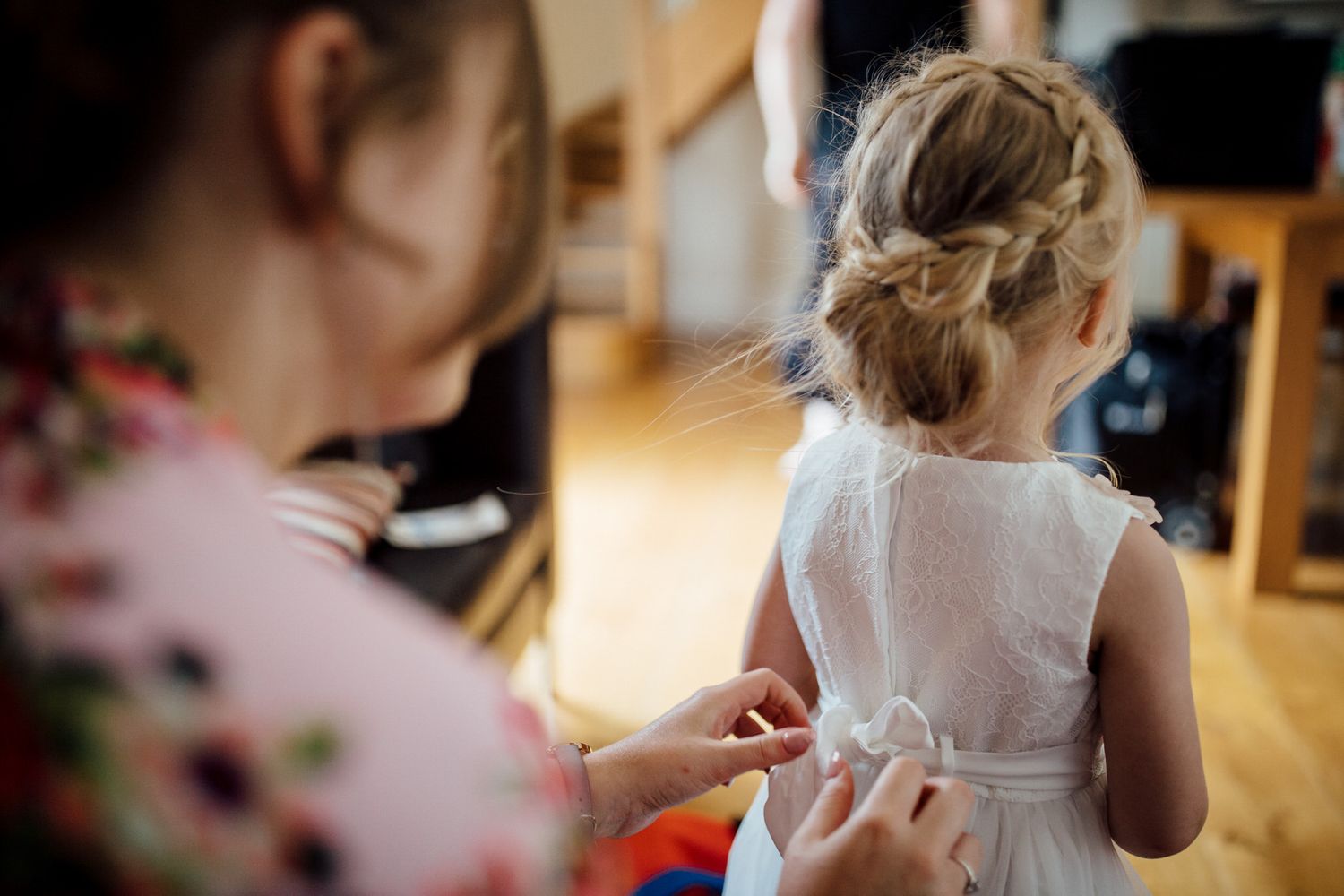 Bride getting ready with her bridesmaids in a sunlit room before the wedding ceremony.