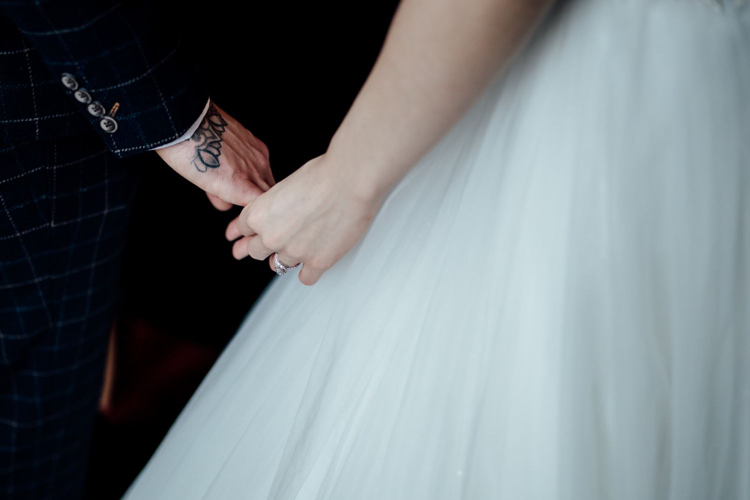 Bride in flowing white gown dances with groom in dark suit during intimate wedding moment.