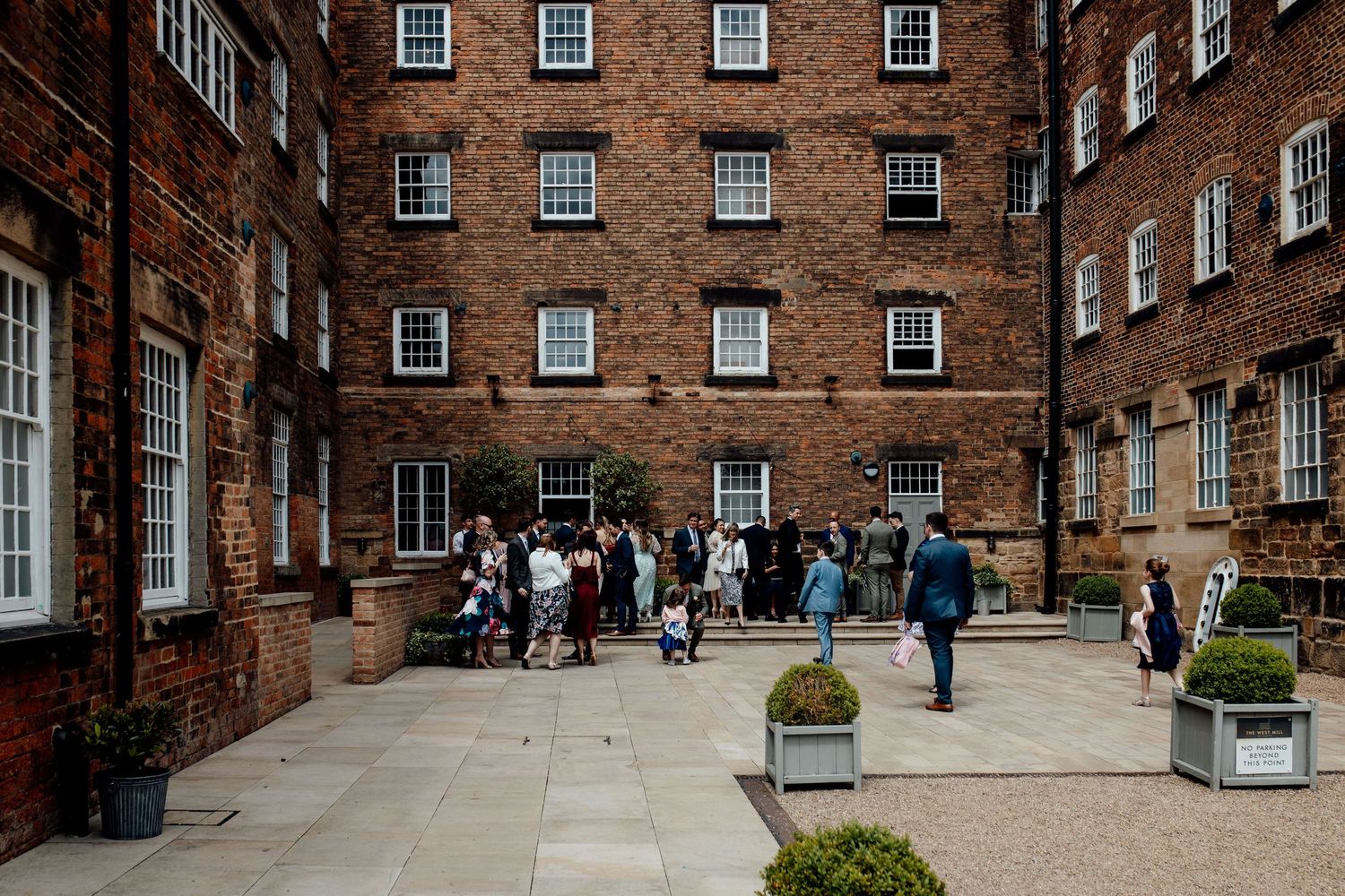 Historic brick courtyard with symmetrical windows serves as wedding venue backdrop.