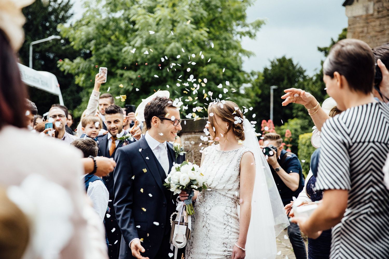 Guests throw confetti over newlyweds during outdoor celebration.