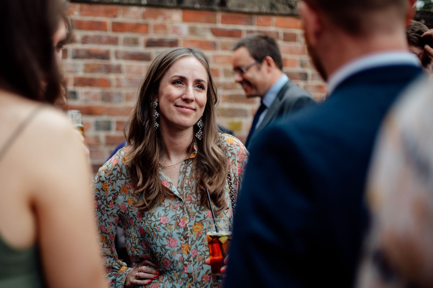 Wedding guests enjoying an outdoor celebration against a rustic brick wall backdrop.