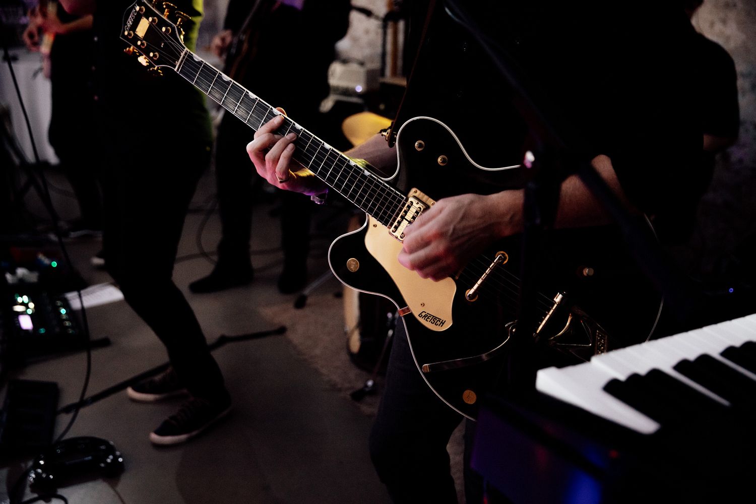 Close-up shot of hands playing black electric guitar during performance.