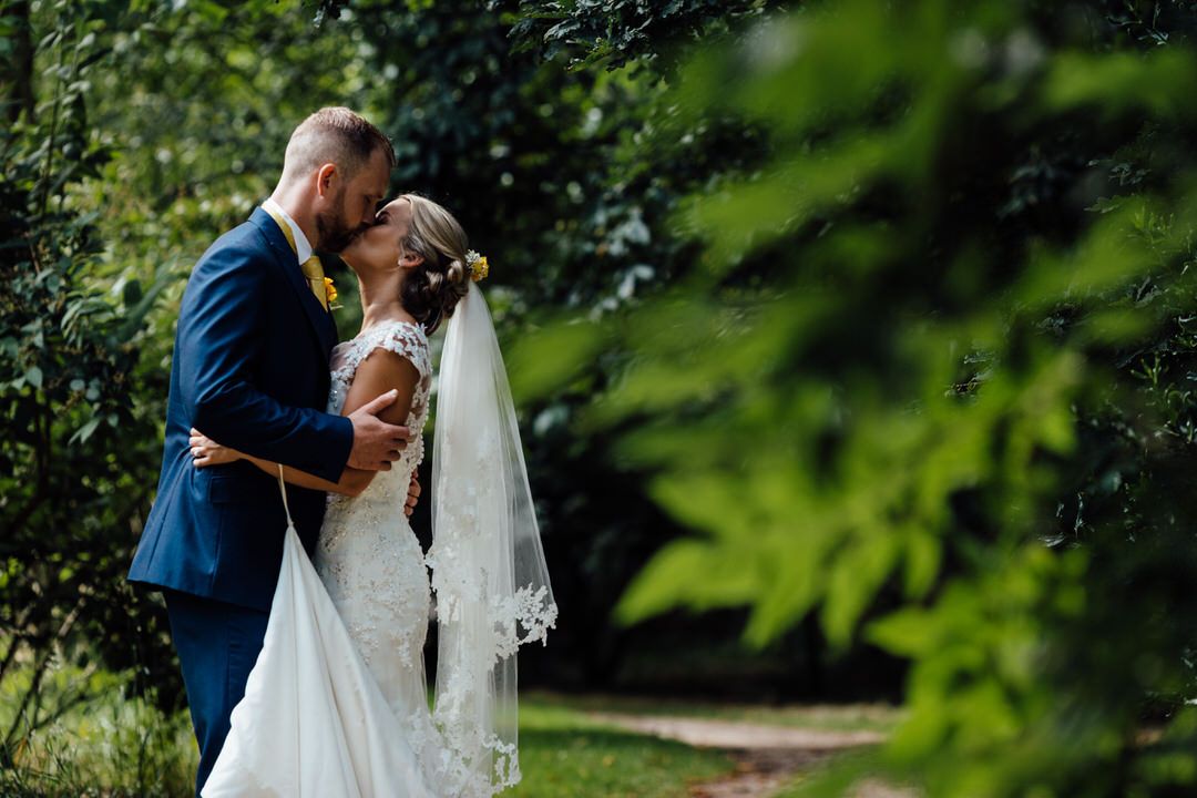 Romantic outdoor wedding portraits among lush green foliage.