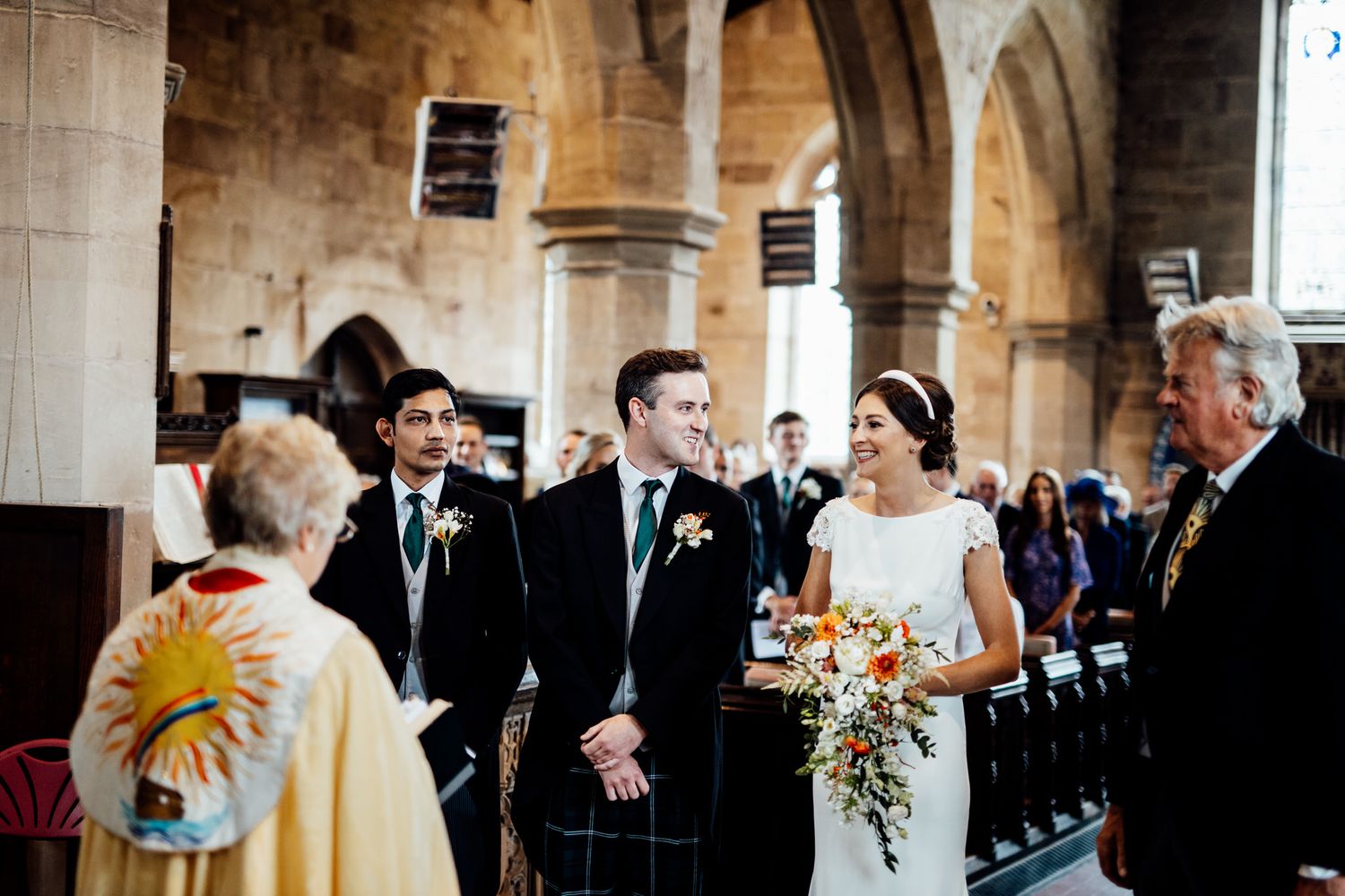 Wedding ceremony in a historic stone church with ornate architectural details.