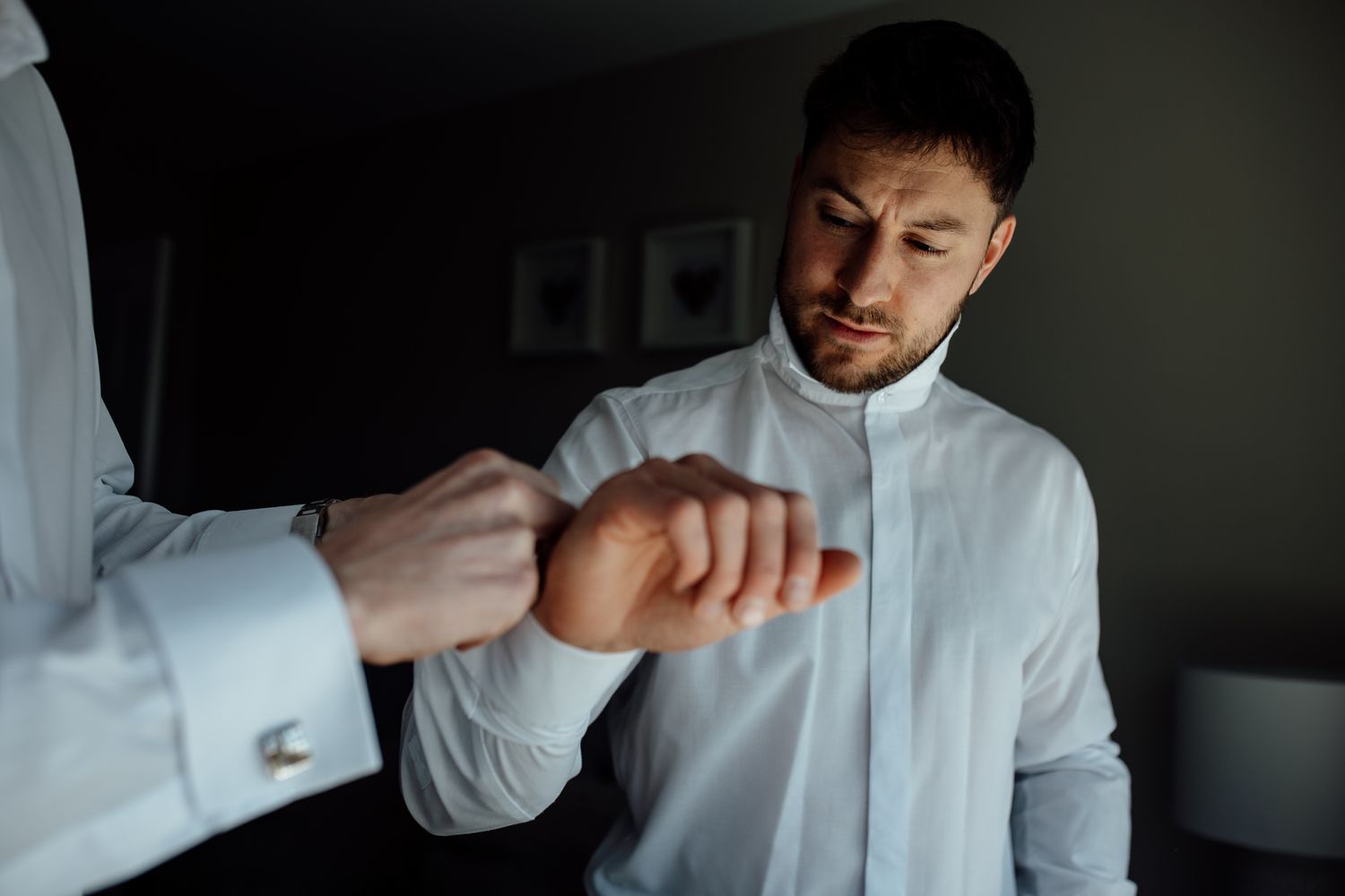 Getting ready scene with white button-up shirts in natural window light.