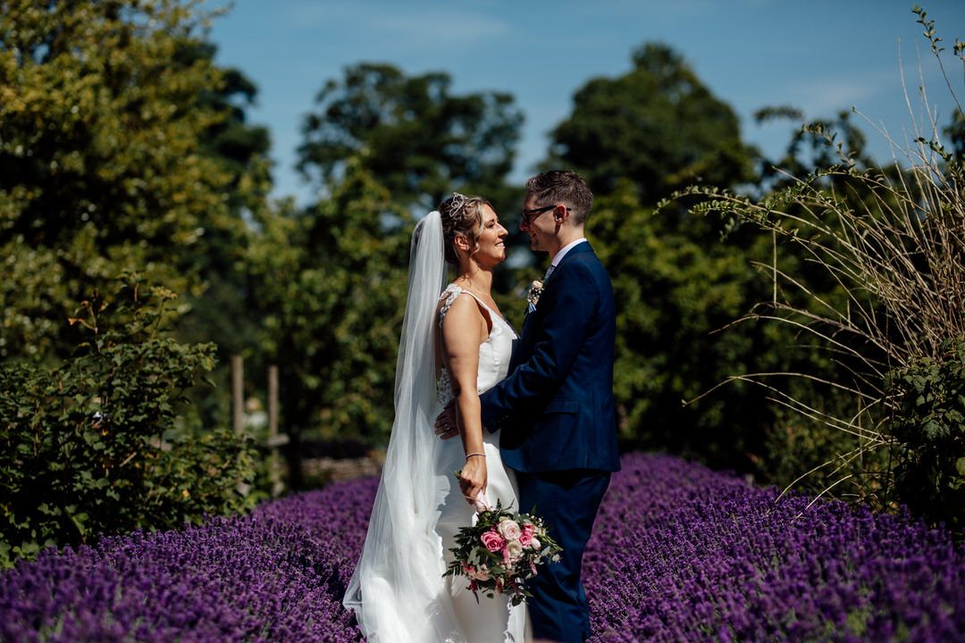 Romantic wedding portraits captured among blooming purple lavender fields.