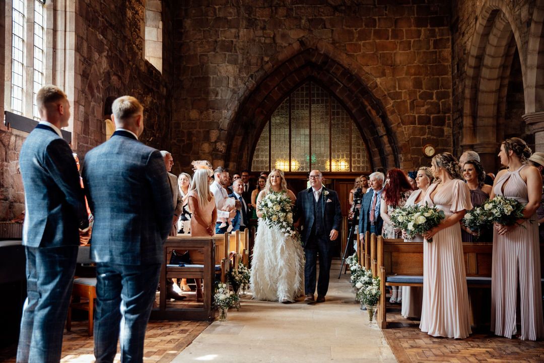 Wedding ceremony in a historic brick church with gothic architecture and floral decorations.