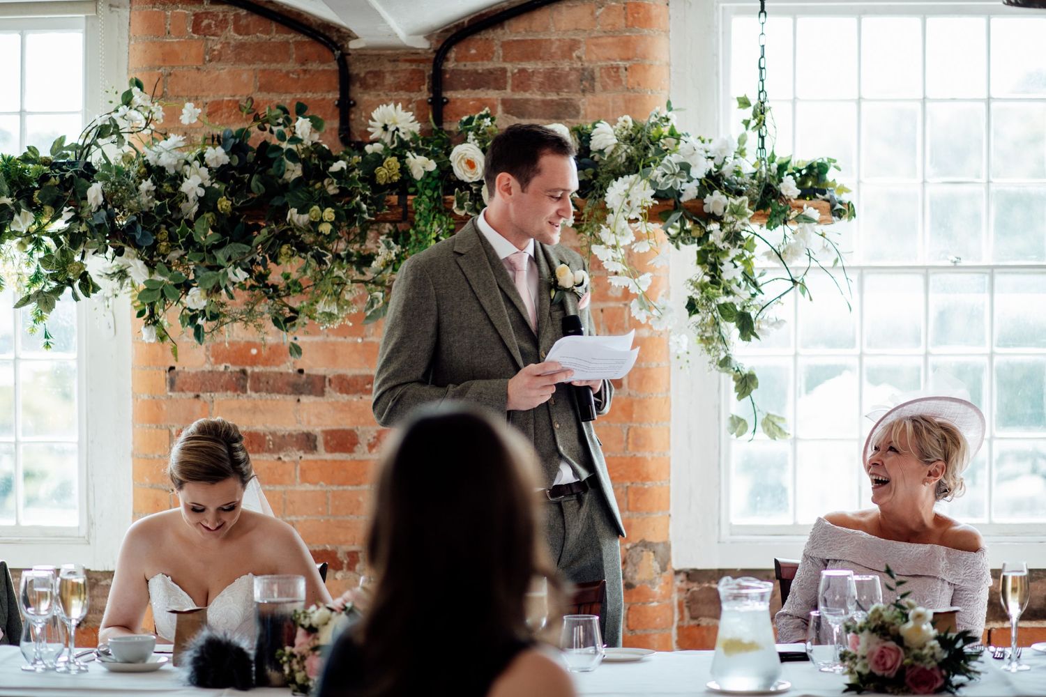 Wedding reception in a bright industrial venue with exposed brick walls and large windows.