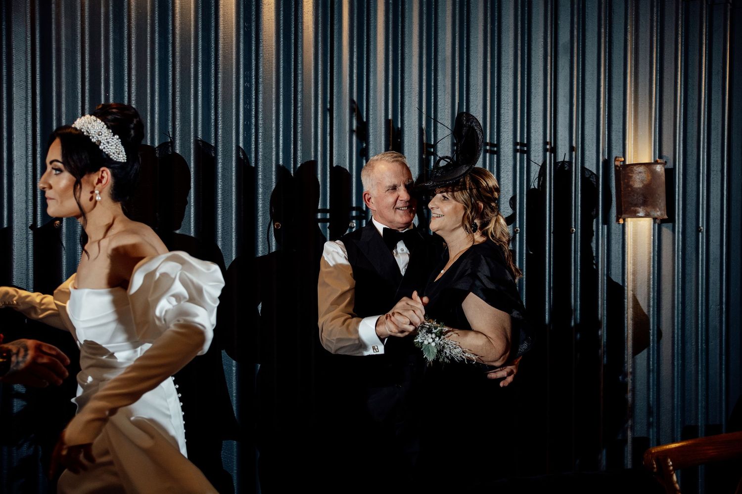 Dance floor filled with guests celebrating at an evening wedding reception with dramatic lighting.