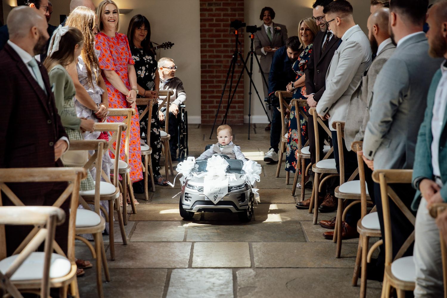 Indoor wedding ceremony setup with wooden chairs and brick walls.