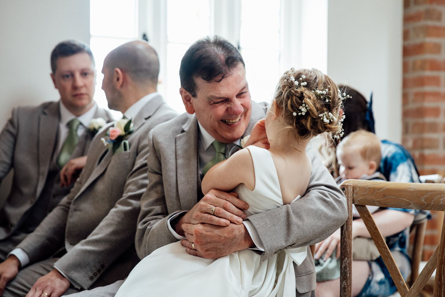 Wedding guests share emotional moments during a ceremony in a bright indoor venue.