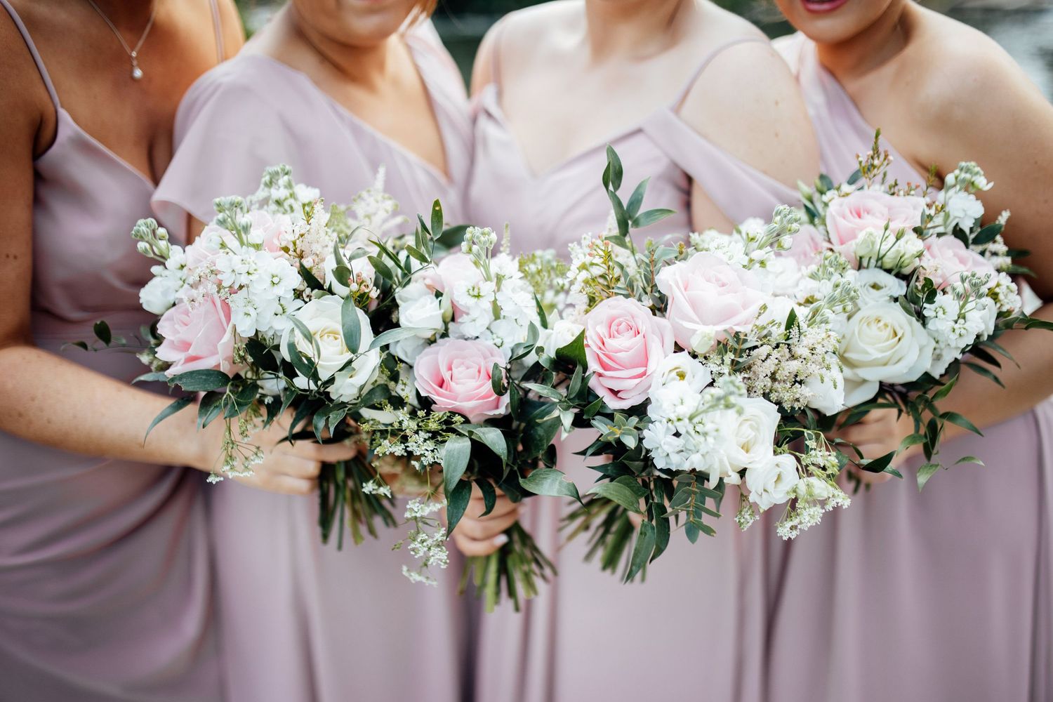 Bridesmaids holding elegant pink and white floral bouquets.