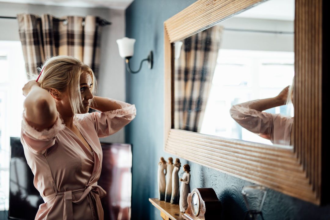 Getting ready moments captured in blue-walled room with plaid curtains.