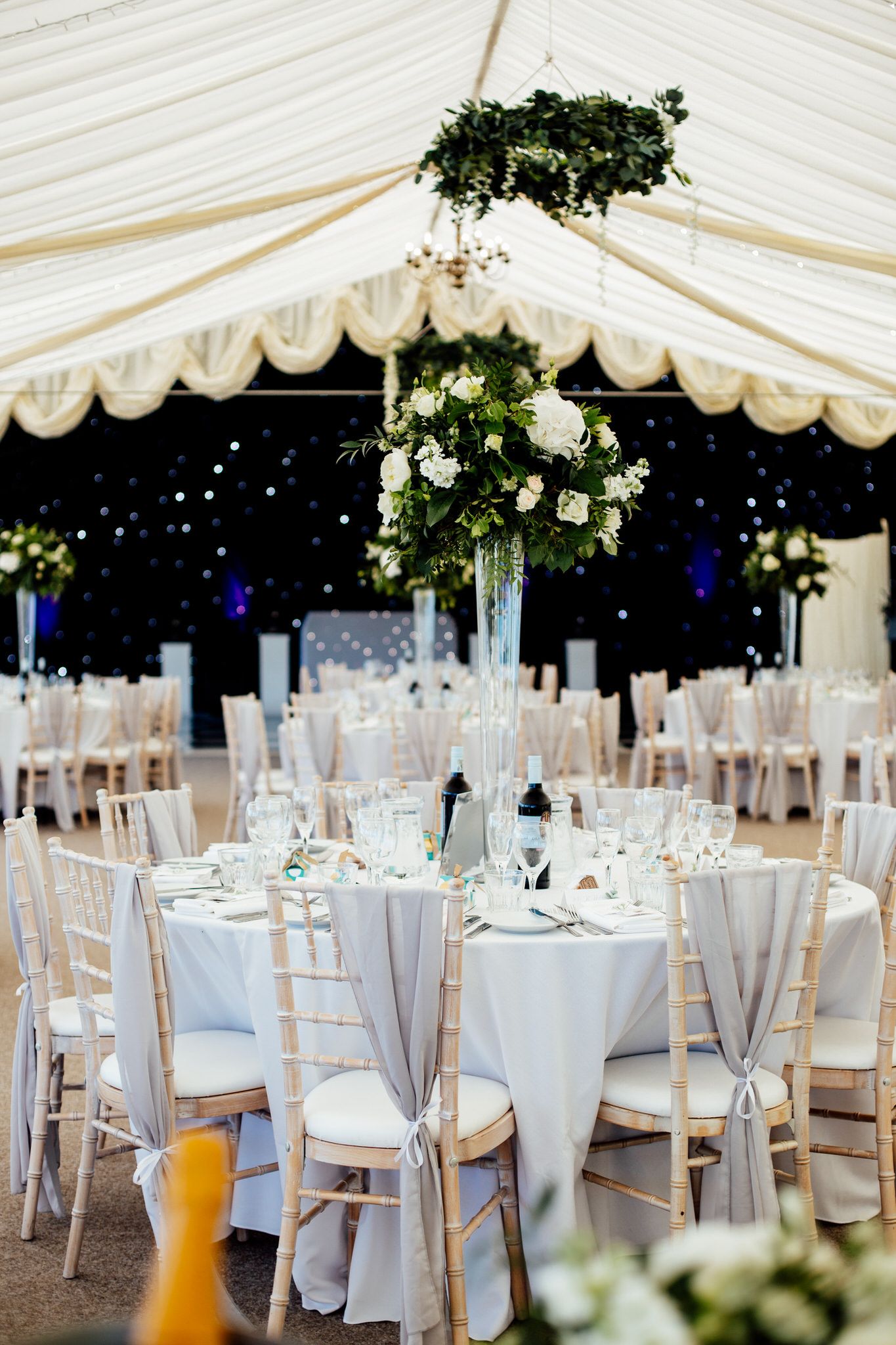 Elegant white wedding marquee with floral decorations and table settings.