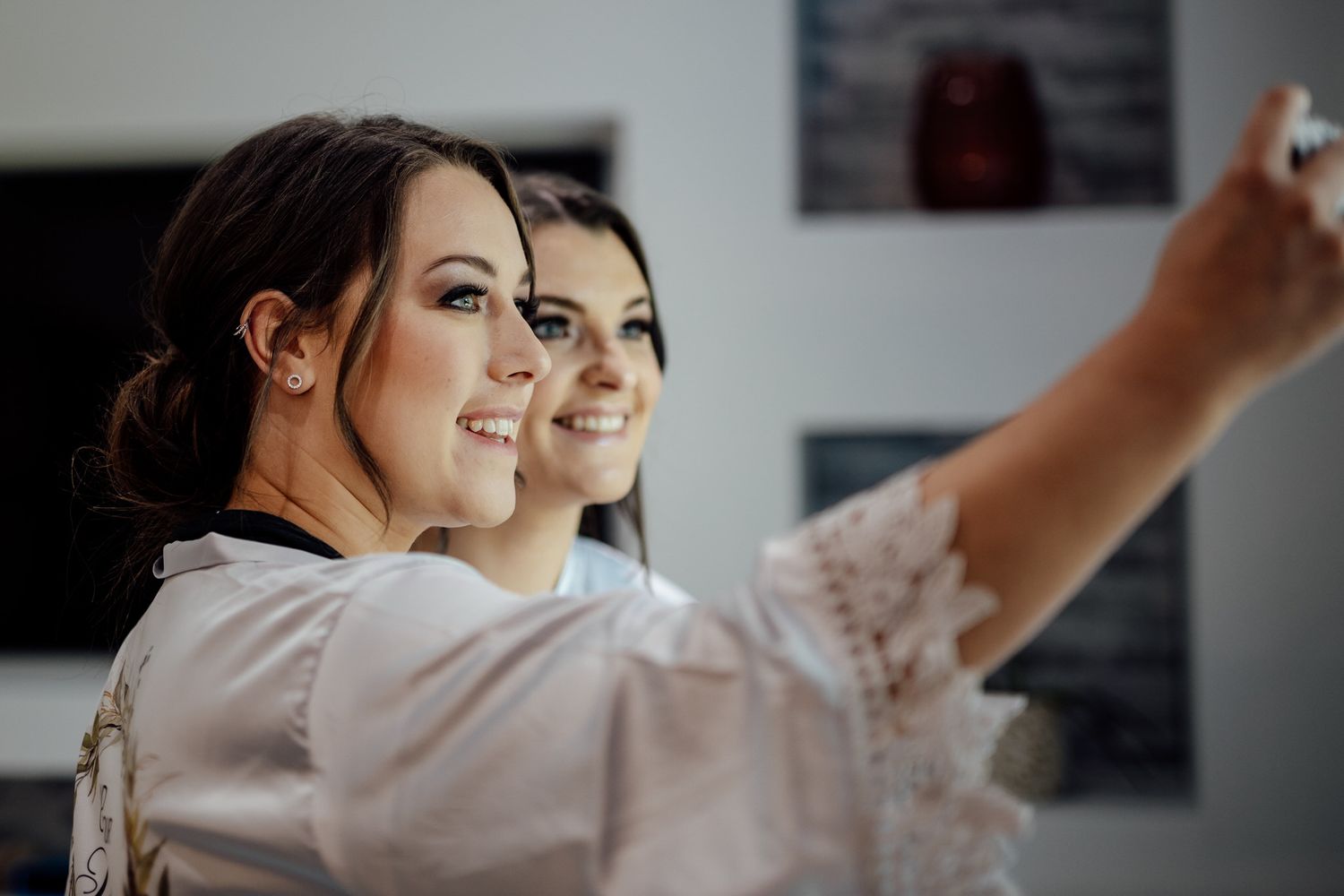 Two women in robes taking a selfie while getting ready.