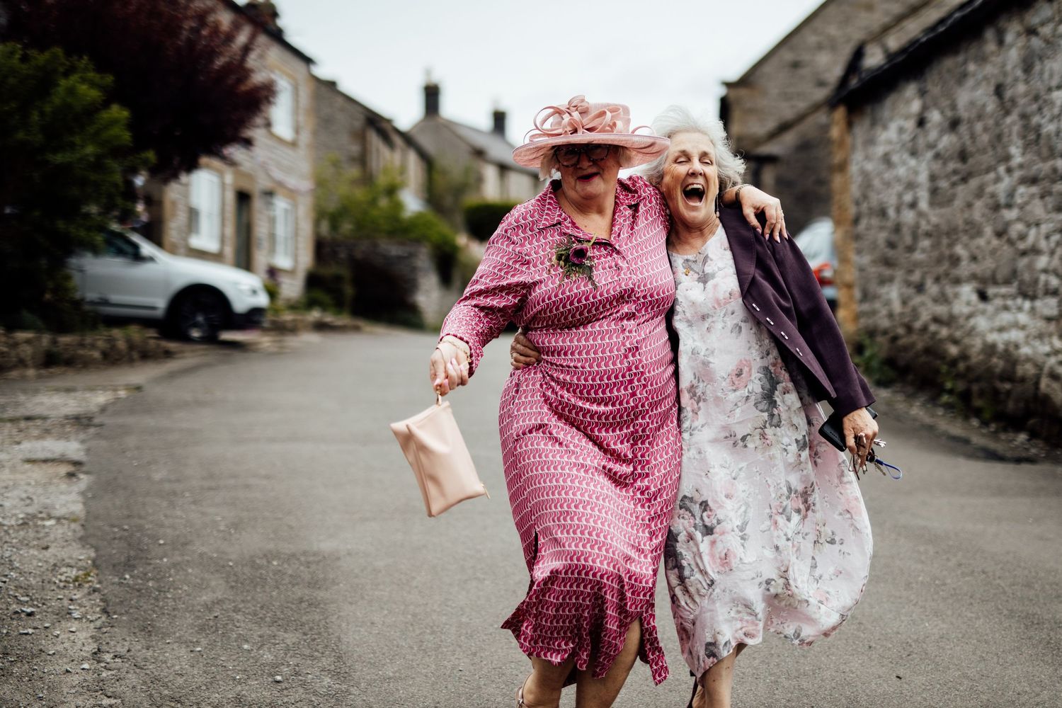 Wedding guests strolling down a charming stone-walled village street.
