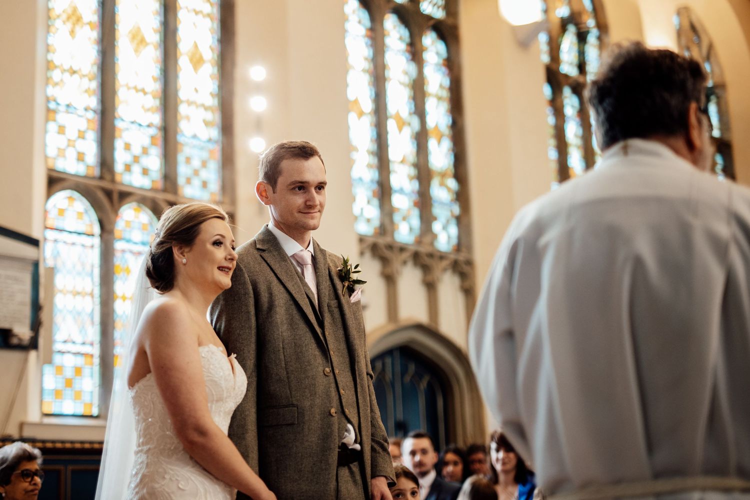 A wedding ceremony in progress inside a beautiful church with stained glass windows.