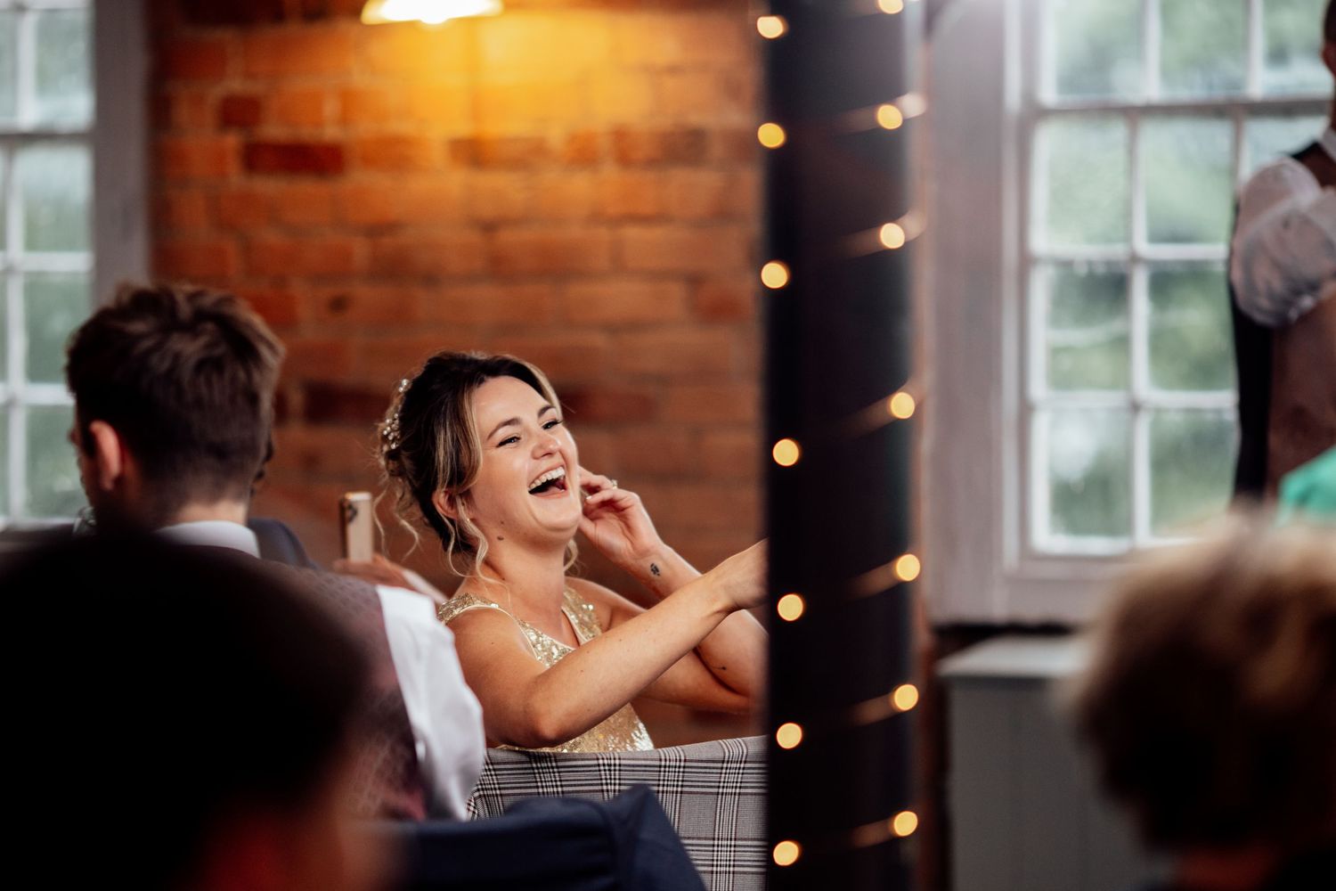Joyful celebration scene in rustic venue with exposed brick walls and string lights.
