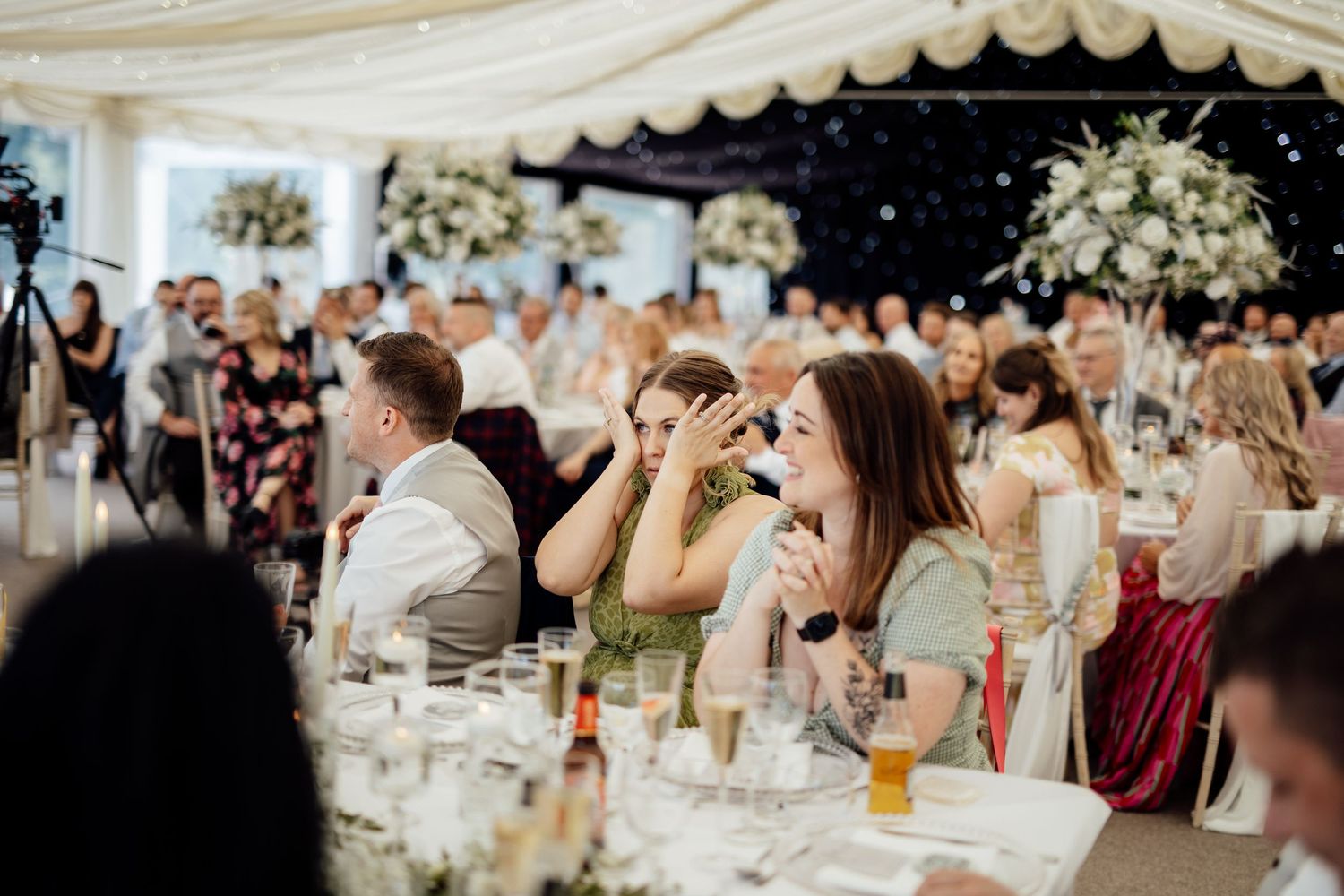 Wedding reception tables decorated with white floral centerpieces and twinkling lights.