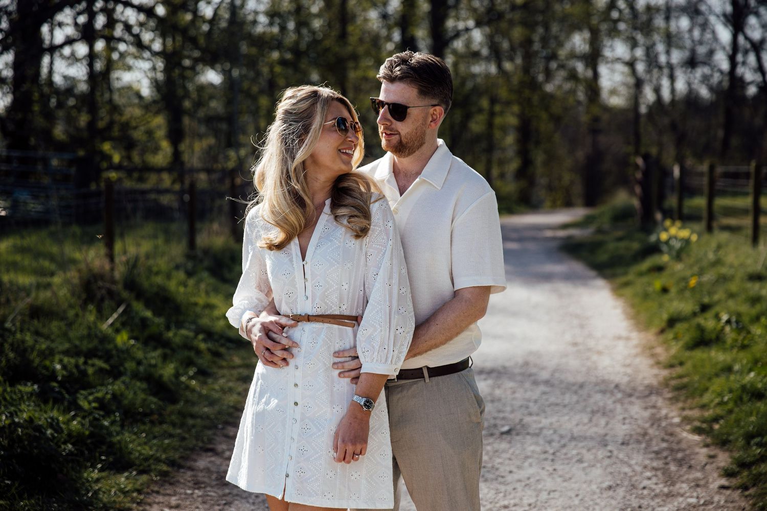 A couple walks hand in hand along a scenic countryside path.